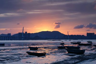 Boats moored on sea against sky during sunset