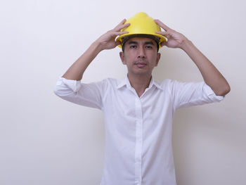 Portrait of young man standing against white background