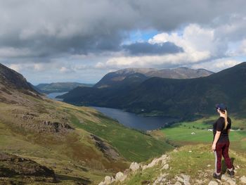 Rear view of woman standing on mountain against sky