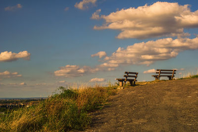 Empty bench on field against sky