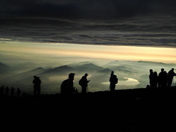 Silhouette people on landscape against scenic sky