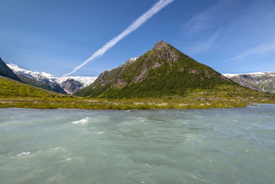 Scenic view of sea by mountains against sky