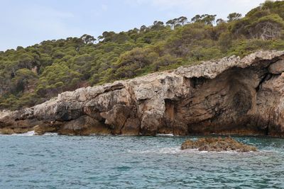 Scenic view of rocks by sea against sky