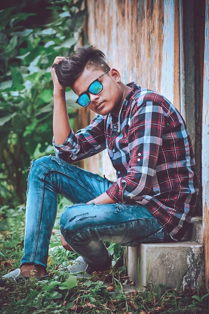 young adult, young men, casual clothing, real people, leisure activity, lifestyles, one person, full length, glasses, sitting, men, day, males, nature, holding, eyeglasses, looking, outdoors, teenager, jeans, plaid shirt
