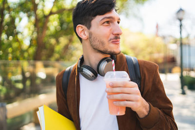 Young man drinking juice while looking away