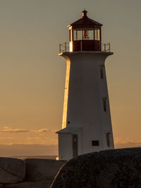 Lighthouse by sea against sky during sunset