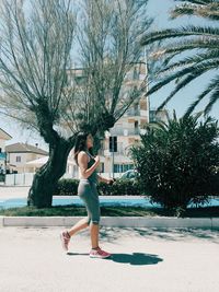 Side view of woman against trees in city