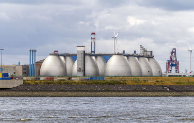 Factory by sea against sky