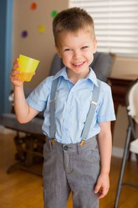 Portrait of smiling cute boy holding drink at school