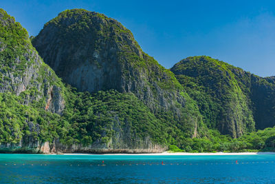 Scenic view of sea and mountains against clear blue sky