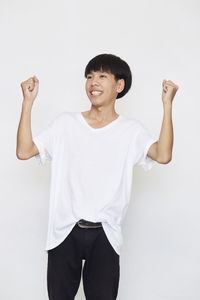 Portrait of smiling young man standing against white background