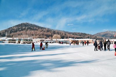 People on snowy mountain against sky