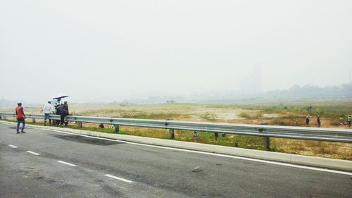 People walking on road against sky