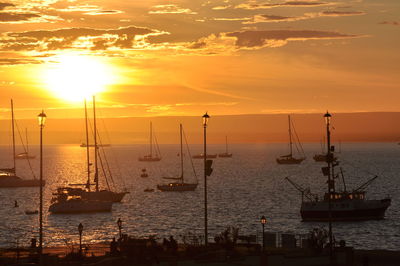 Sailboats moored on sea against sky during sunset