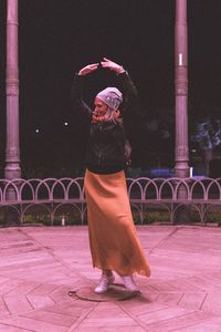 Rear view of woman with umbrella walking at night