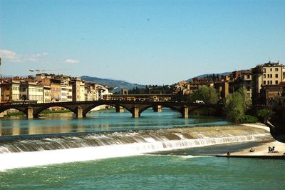 Arch bridge over river against blue sky