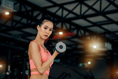 Portrait of young woman standing against illuminated lights