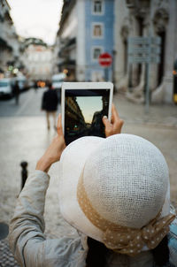 Rear view of woman photographing on street