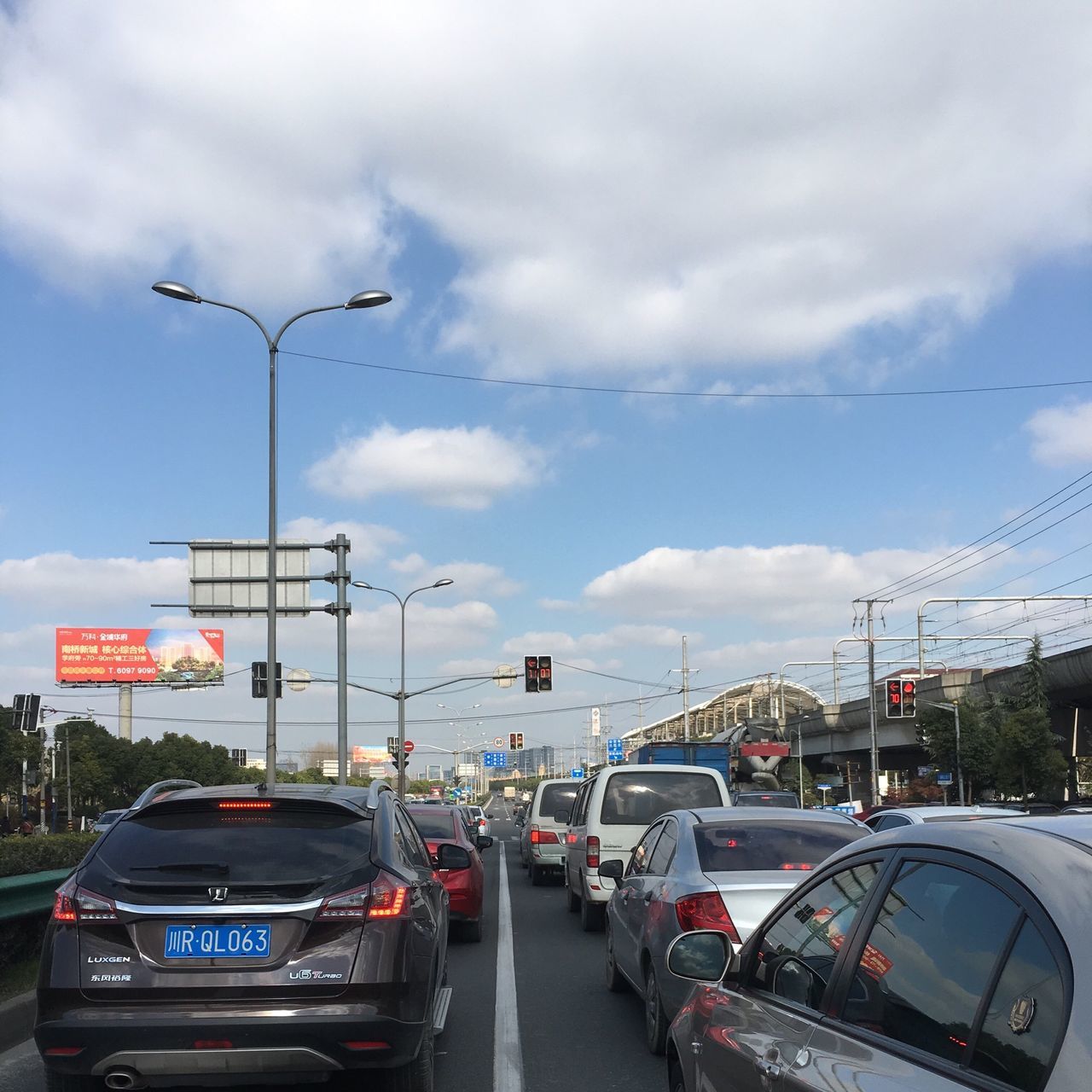 transportation, car, land vehicle, mode of transport, sky, road, street, cloud - sky, street light, on the move, cloudy, traffic, road marking, cloud, travel, city, power line, building exterior, city street, road sign