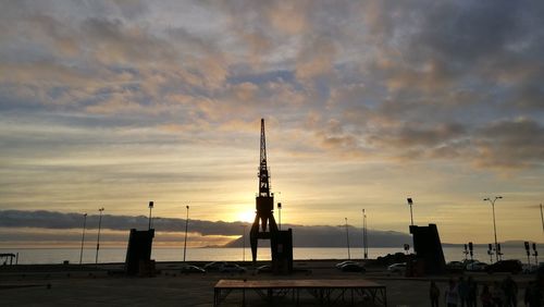 Silhouette cranes against sky during sunset