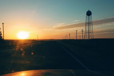 Empty road along countryside landscape at sunset