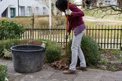 Woman cleaning while standing by plants