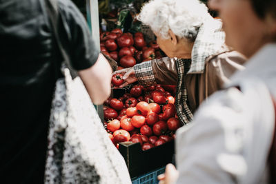 Midsection of woman holding fruits at market stall