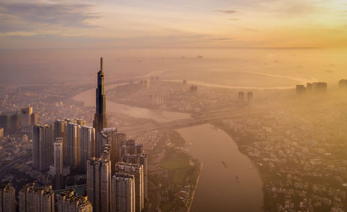 Aerial view of buildings in city at sunset