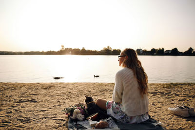 Woman sitting on beach against clear sky