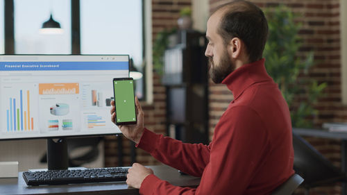 Side view of man using mobile phone in office