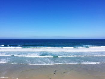 View of calm beach against clear blue sky