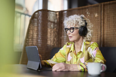 Senior woman in headphones using tablet