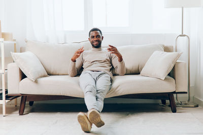 Portrait of young woman sitting on sofa at home