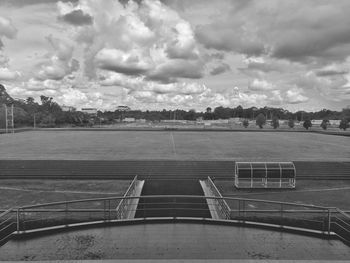 Empty benches by lake against sky