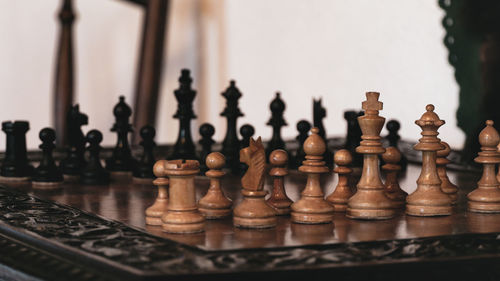 Close up view of unique wood hand crafted chess set pieces on wooden chess board