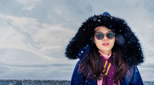 Portrait of beautiful woman standing against sky during winter