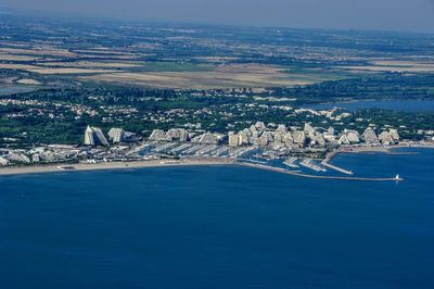 Aerial view of city by sea against sky