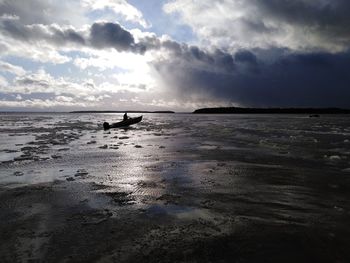 Silhouette people on beach against sky