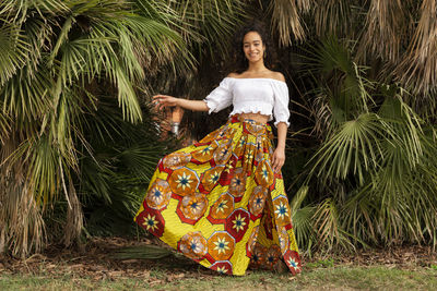 Portrait of a smiling young woman standing against plants