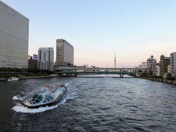 Bridge over river by buildings against sky in city