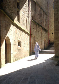 Rear view of woman walking on cobblestone street