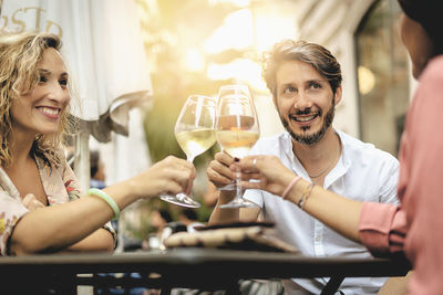 Smiling friends toasting wineglasses at restaurant