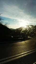 Cars on road against cloudy sky