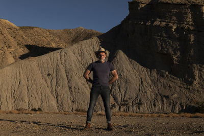 Adult man in cowboy hat on desert against mountain. almeria, spain