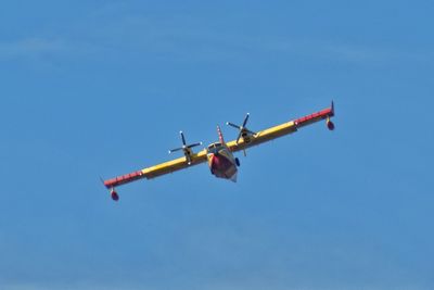 Low angle view of airplane flying against blue sky