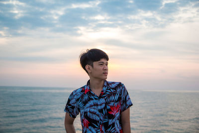 Full length of teenage girl standing in sea against sky