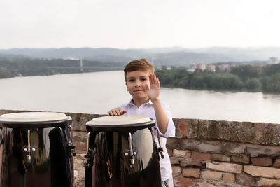 Happy kid playing bongos by the river.