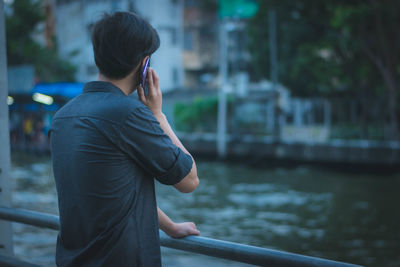 Man talking on mobile phone against pond