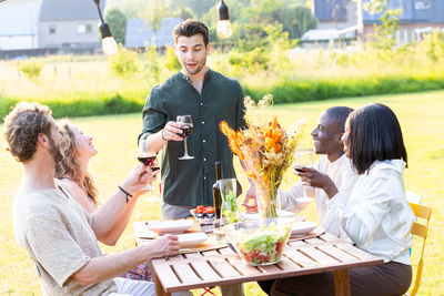 Smiling friends using mobile phone while sitting on table