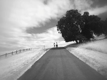 Distant view of girl and woman on road against sky